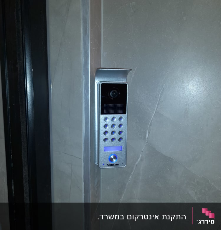 אינטרקום עם מצלמה ולוח מקשים על קיר